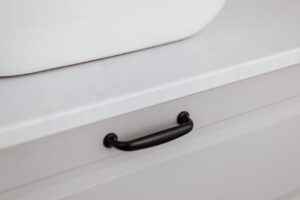Close-up of a modern black handle on a white drawer, showcasing minimalist interior design.