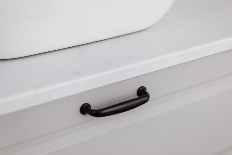 Close-up of a modern black handle on a white drawer, showcasing minimalist interior design.