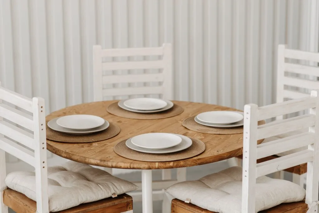 Cozy dining setup with wooden table, ceramic plates, and cushioned chairs in a minimalist style.