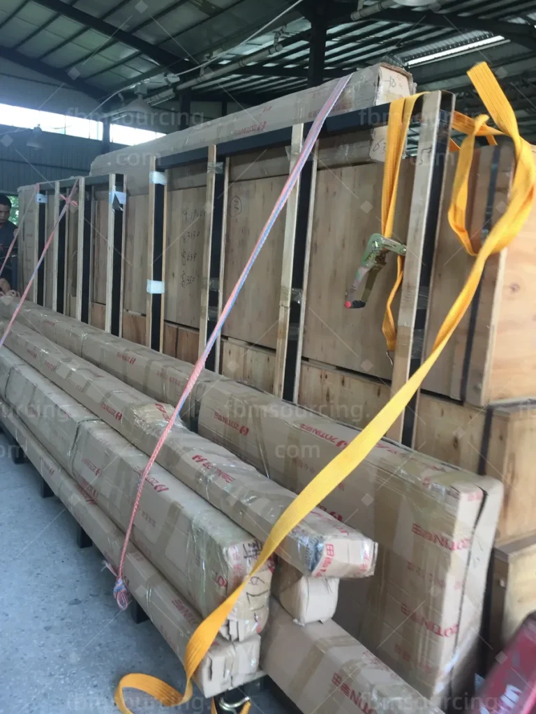 Strapped bundles of packed frames staged outdoors before container stuffing