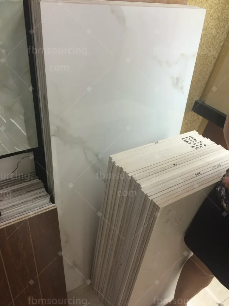 Marble-look porcelain tiles stacked for client review during the sourcing trip