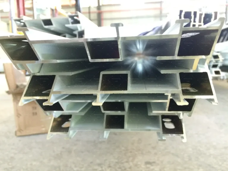 Aluminium window profile cross-sections stacked for inspection at the fabrication factory