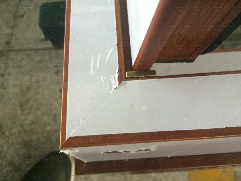 Mitred corner joint of a wood-grain aluminium window inspected for tight seams