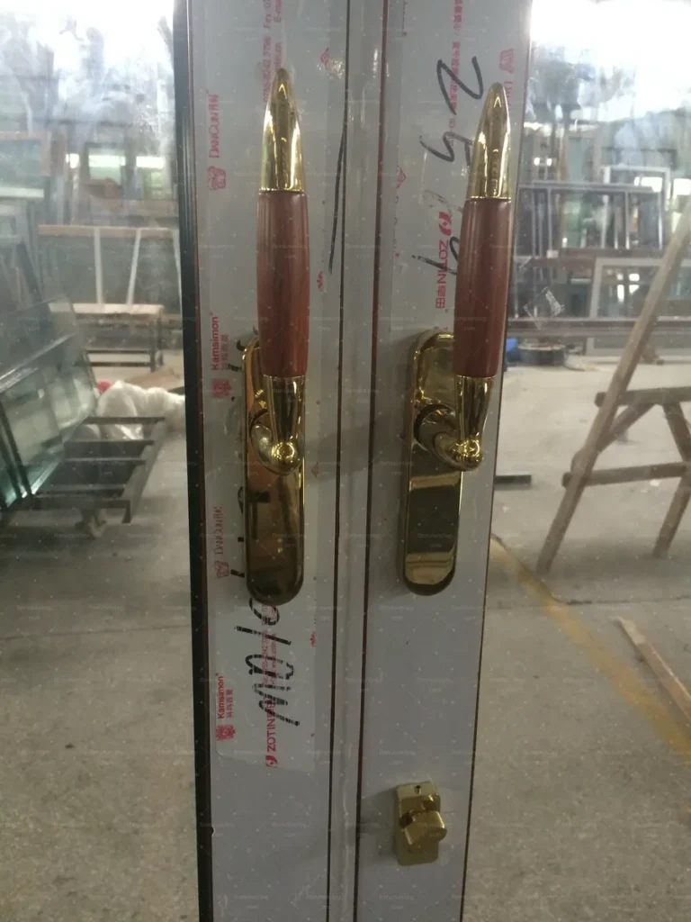 Brass lever handles fitted to timber-look entrance doors during final checks