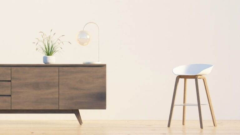 Modern minimalist interior featuring a wooden sideboard, chair, lamp, and plant against a white wall.