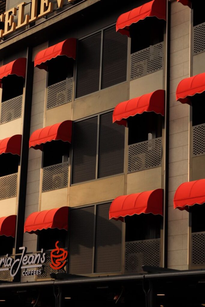Vertical shot of a building facade in Ankara featuring red awnings and windows.