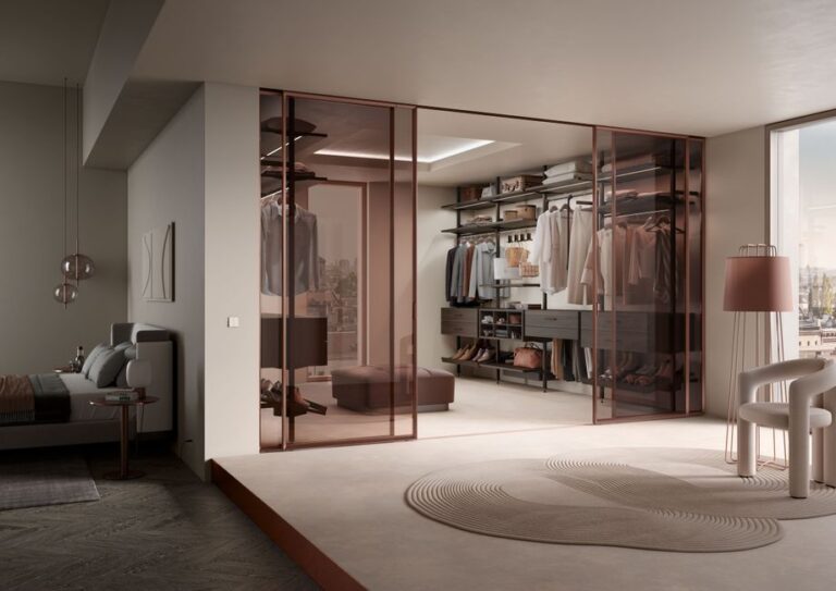 Elegant modern walk-in wardrobe with glass doors in a spacious bedroom setting.