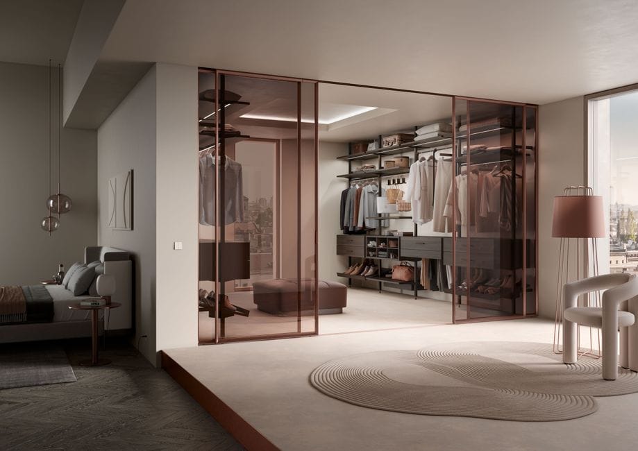 Elegant modern walk-in wardrobe with glass doors in a spacious bedroom setting.
