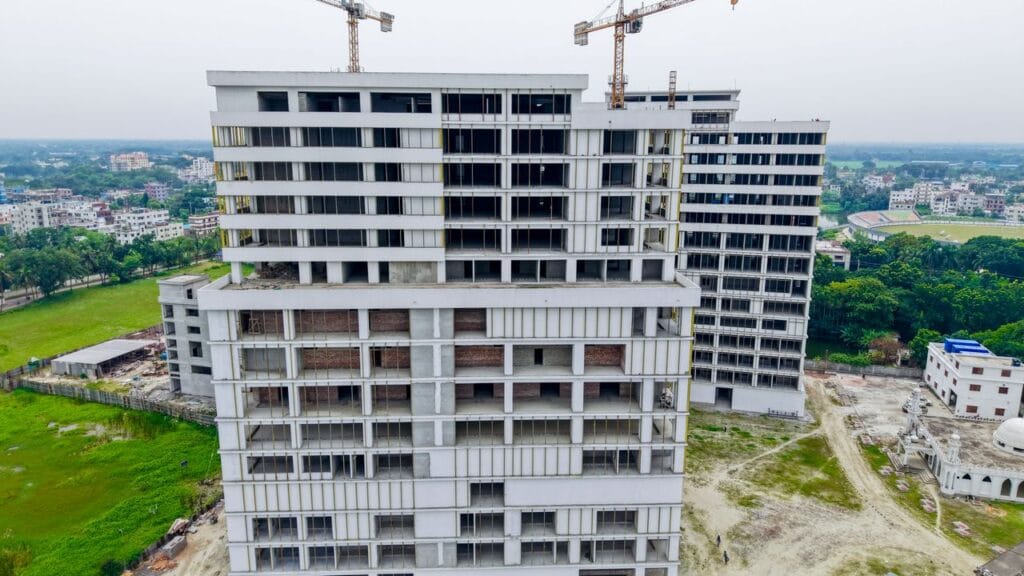 Aerial shot showcasing a high-rise building under construction with cranes against a cityscape backdrop.