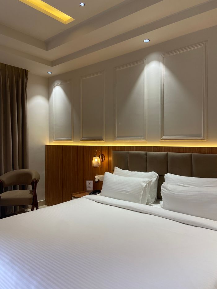 Luxurious hotel room with modern lighting, neutral tones, and cozy bedding.