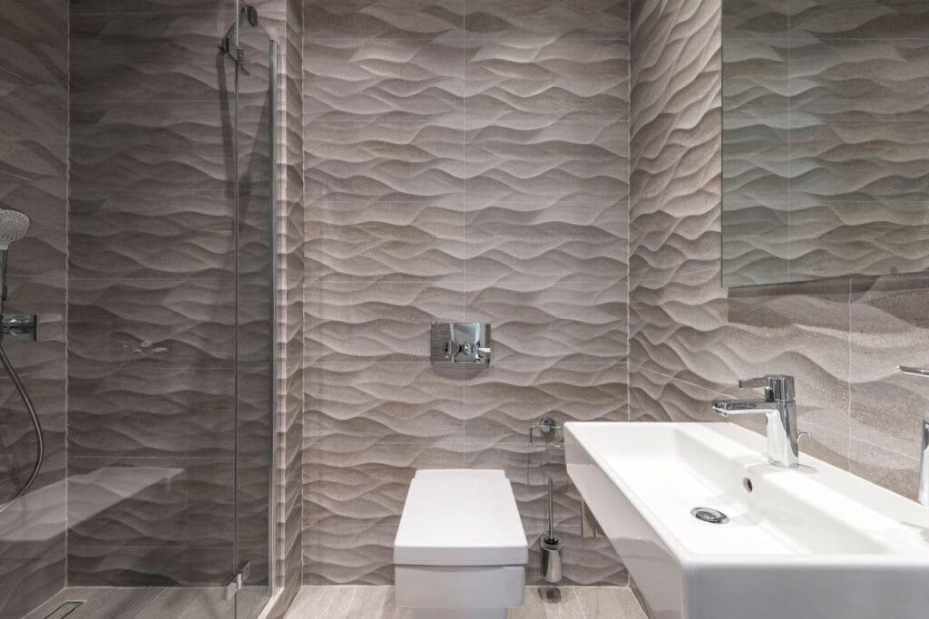 Sleek bathroom featuring textured walls, a glass shower, and a modern sink.