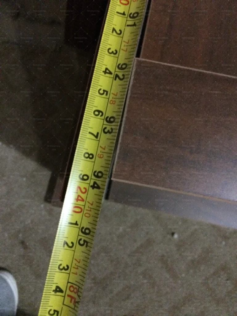 Tape measure check on a hardwood furniture panel during pre-shipment QC