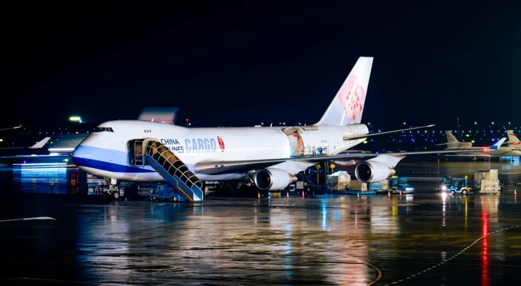 Cargo aircraft being loaded at night, illustrating air freight versus sea freight on a China project order