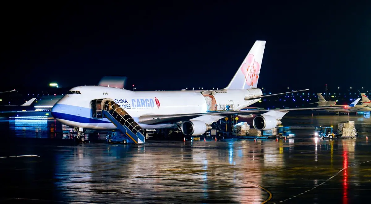 Cargo aircraft being loaded at night, illustrating air freight versus sea freight on a China project order