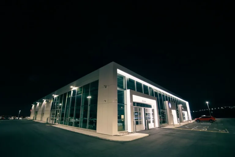 Illuminated glass-facade car dealership showroom building at night