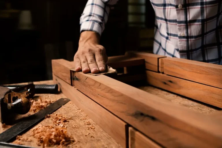 Craftsman finishing a wooden furniture frame in a manufacturing workshop, FF&E warranty and quality