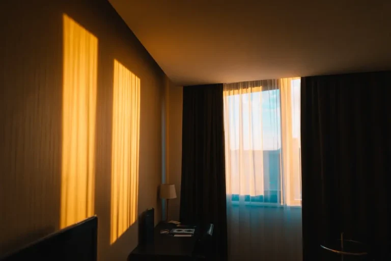 Hotel guest room window with layered sheer and blackout curtains - hotel window treatments from China