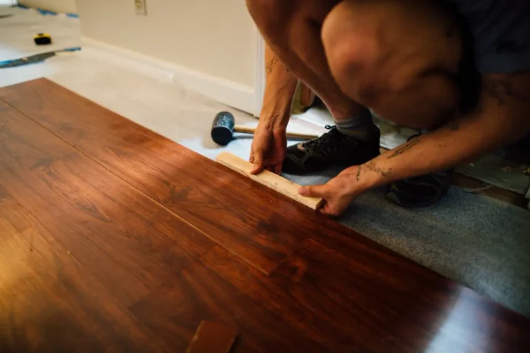 Installer laying laminate wood flooring planks sourced from China flooring manufacturers