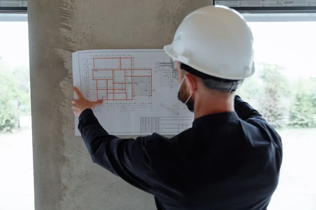 Project manager reviewing floor plan on site — lead-time buffer for China procurement in a construction schedule