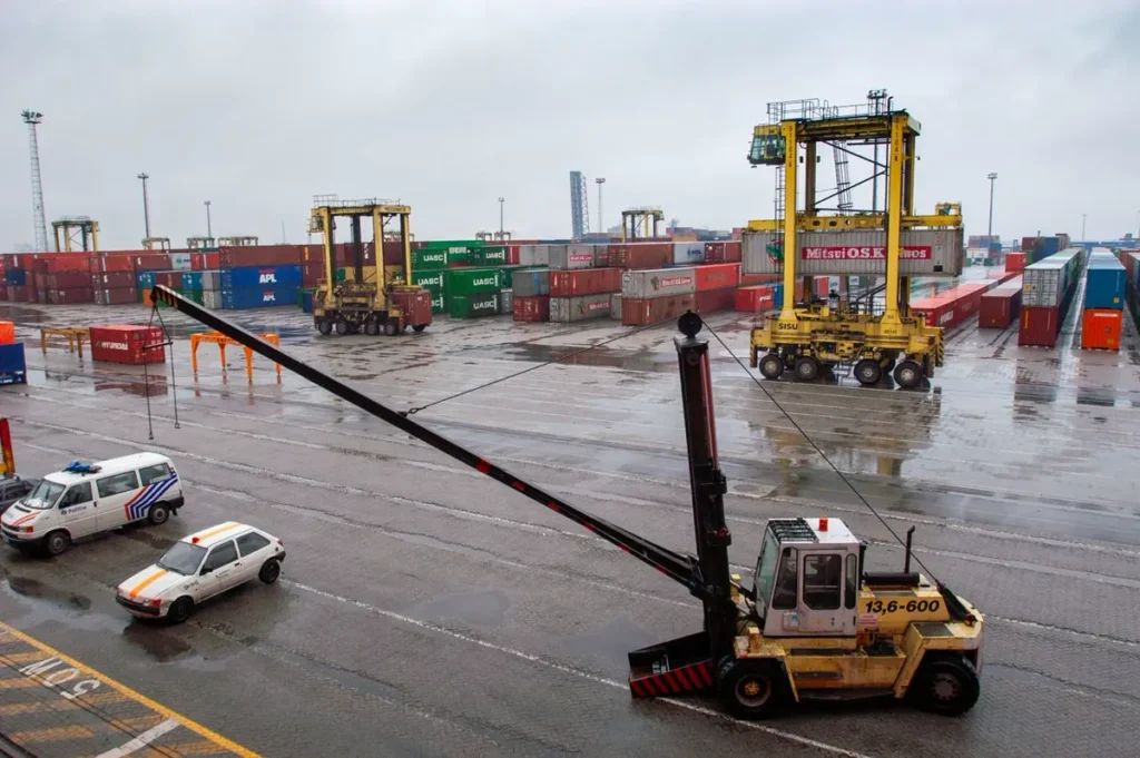 Reach stacker and straddle carrier handling containers in a port yard, illustrating oversized shipping from China by flat rack, open top and breakbulk