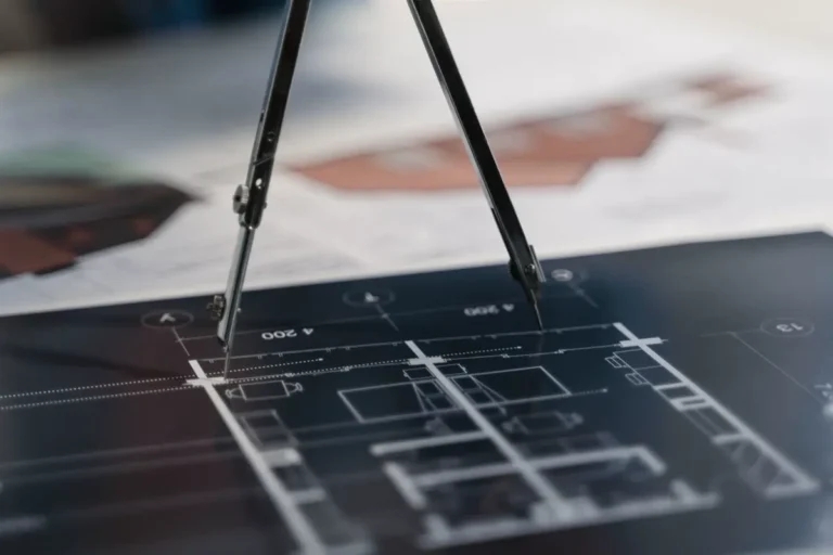 Drafting compass on architectural floor plan drawings prepared for a China sourcing RFQ package