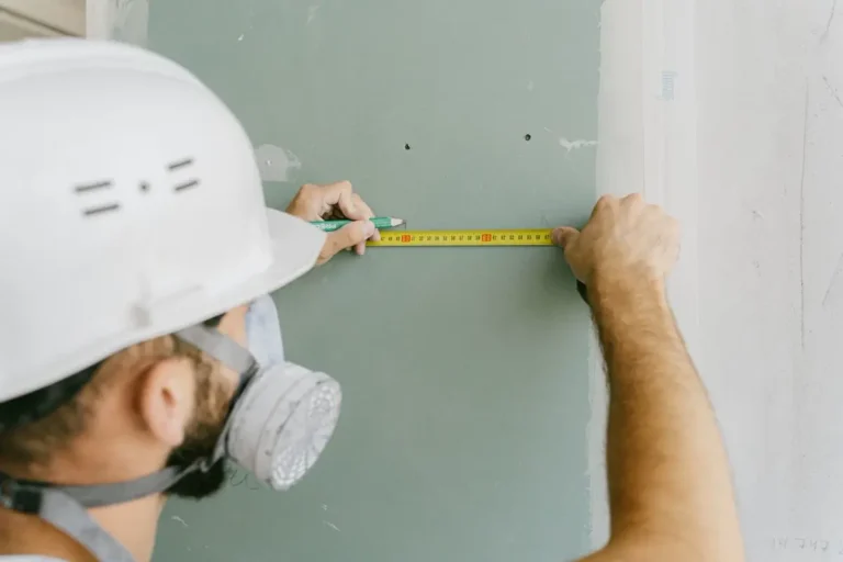 Installer taking an as-built wall dimension — site measurement for custom joinery before China production