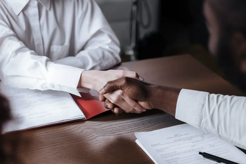 Business handshake over procurement documents representing a China sourcing partner agreement