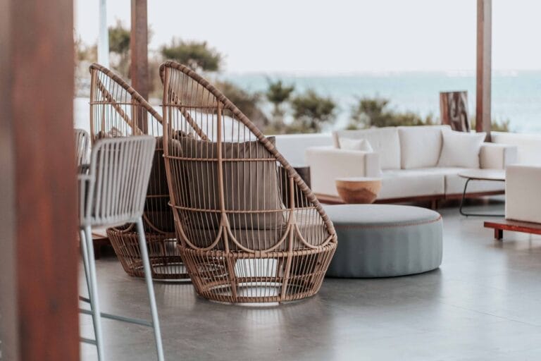 Coastal hospitality terrace with woven outdoor lounge chairs and sofas