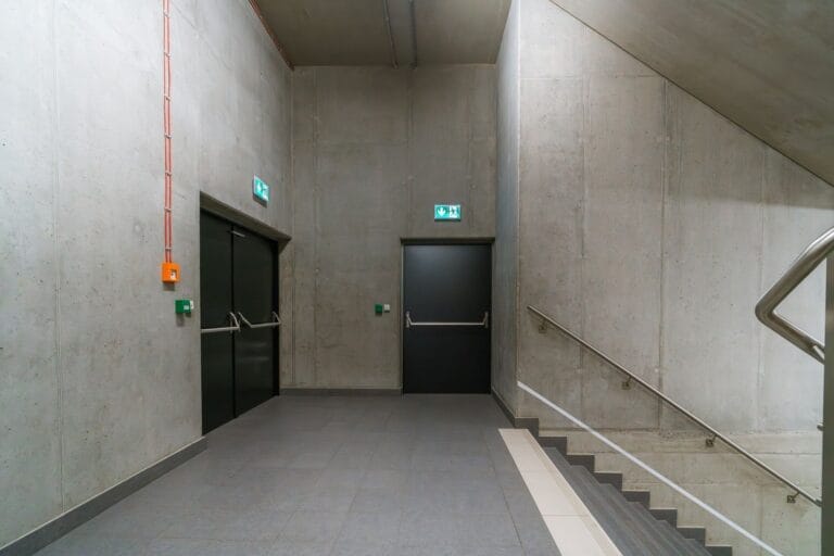 Fire-rated doors in a concrete corridor with exit signs
