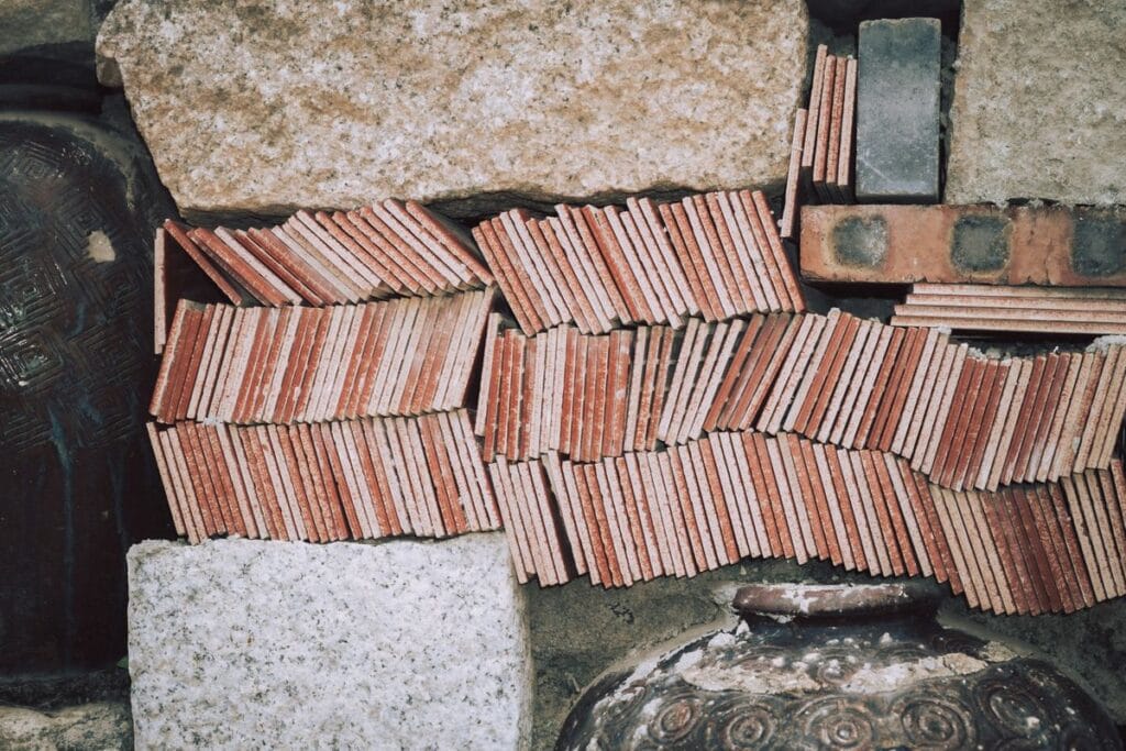 Stacked terracotta tiles, stone slabs and brick, illustrating building materials subject to GCC conformity schemes in Qatar, Kuwait, Oman and Bahrain