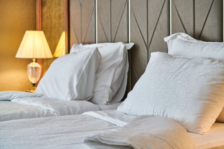 Hotel guestroom bed with upholstered headboard and bedside lamp