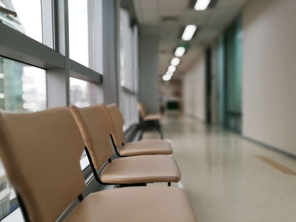 Hospital corridor waiting area with rows of upholstered seating