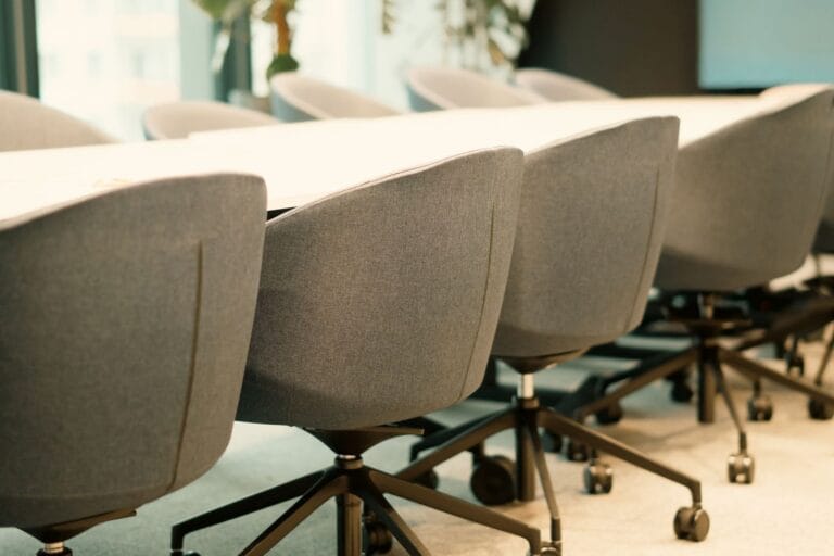 Row of upholstered office meeting chairs on castors along a conference table