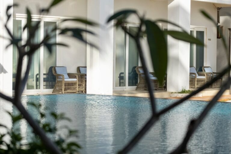 Woven resort armchairs with cushions on covered terraces beside a hotel pool