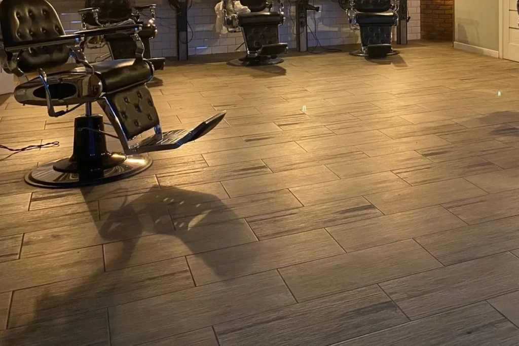 Barbershop interior with reclining barber chairs on wood-look porcelain tile