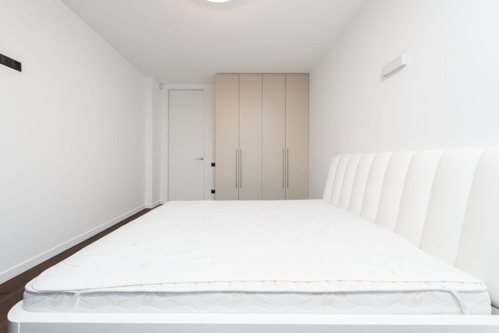 Bedroom with a new white mattress and built-in wardrobe