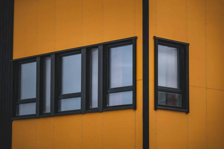 Black-framed windows in a commercial building facade, representing aluminium window and door packages for UK and European projects