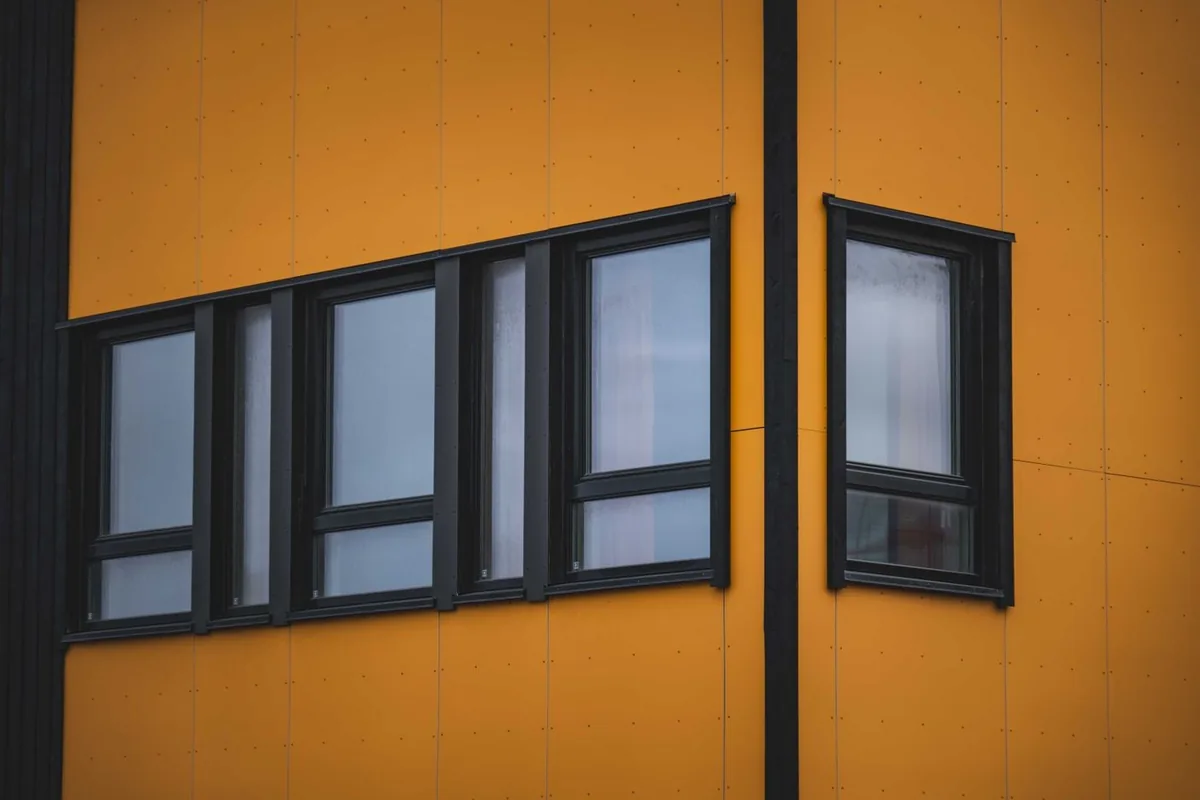 Black-framed windows in a commercial building facade, representing aluminium window and door packages for UK and European projects