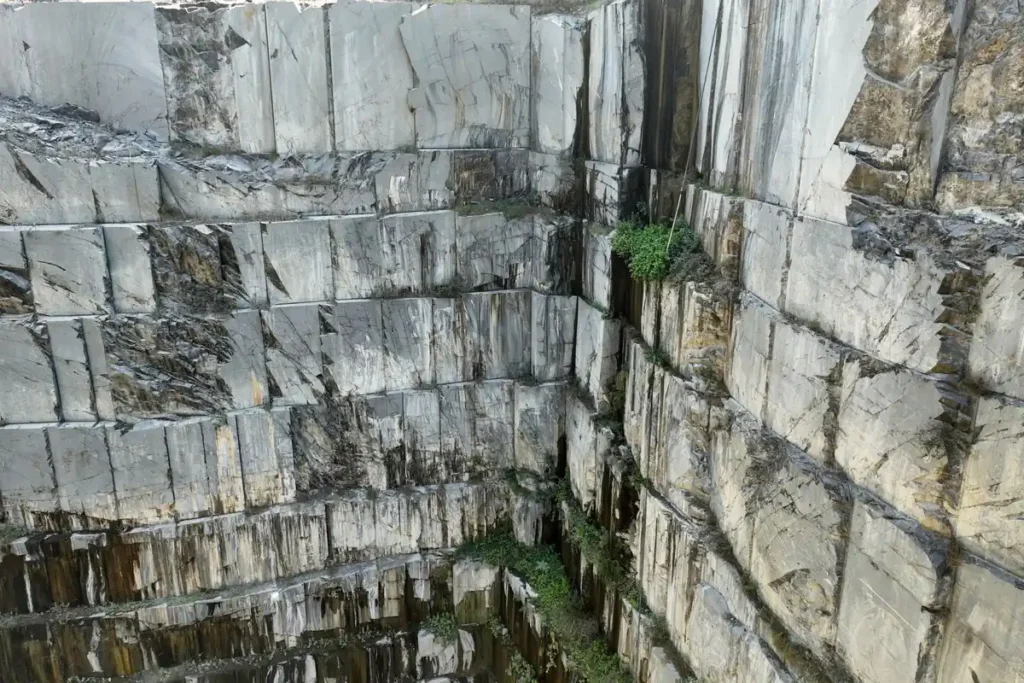 Stepped granite quarry wall with cut stone blocks, natural stone supply for commercial projects