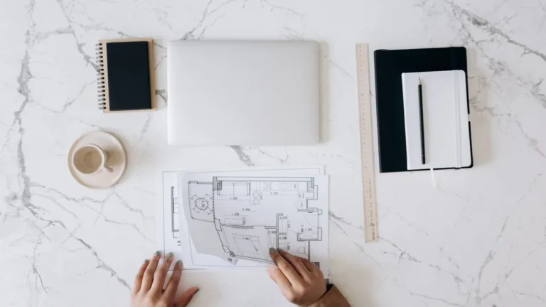 Architectural floor plan on a marble desk with a notebook and ruler