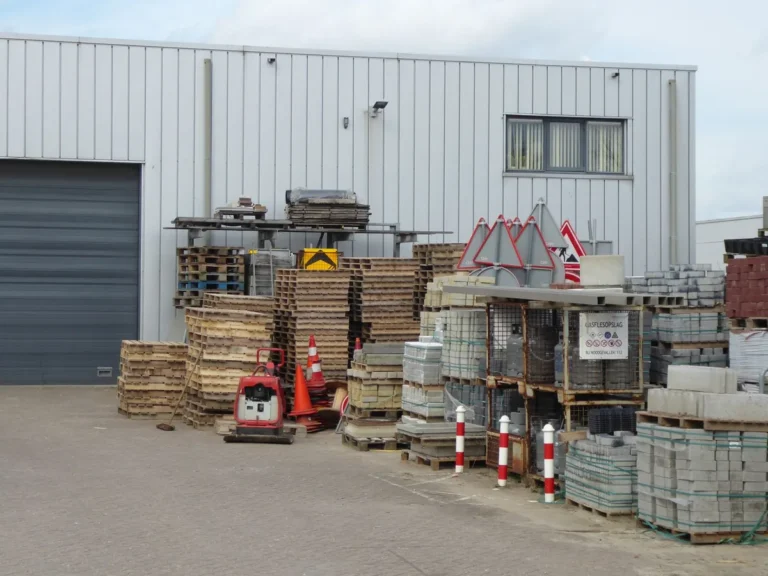 Outdoor yard beside a warehouse with building supplies and materials stacked on pallets