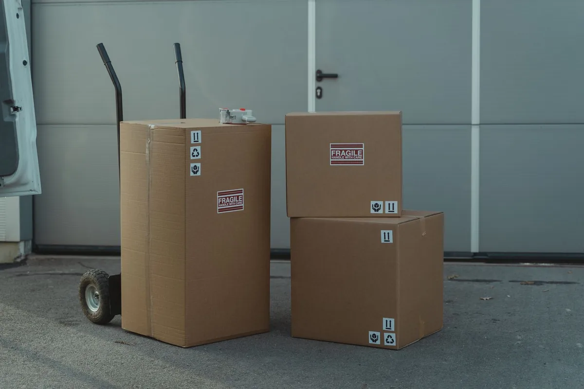Cardboard boxes with fragile labels next to a hand truck