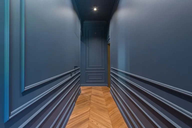 Corridor with painted wall mouldings and a herringbone timber floor