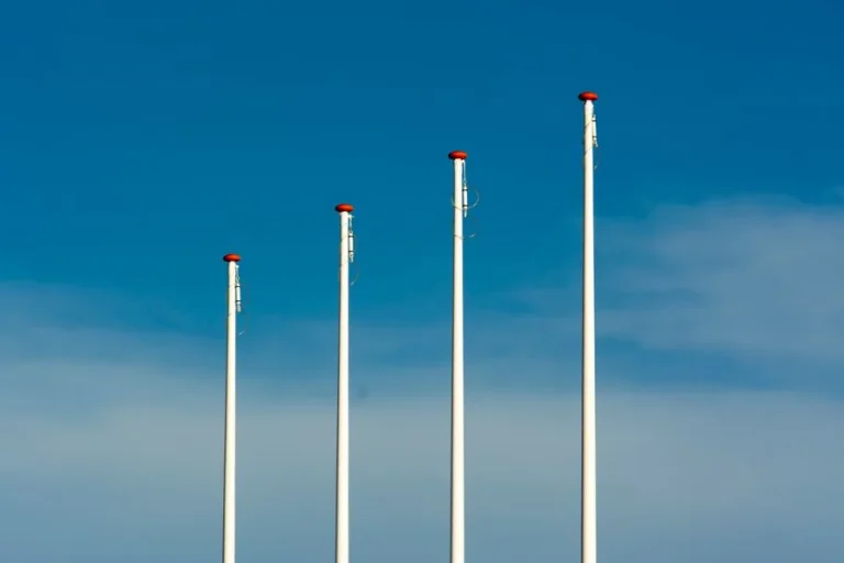 Four tall flagpoles against a blue sky