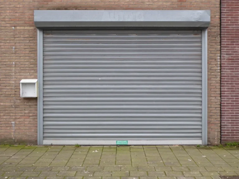 Closed grey metal roller shutter door set in a brick wall