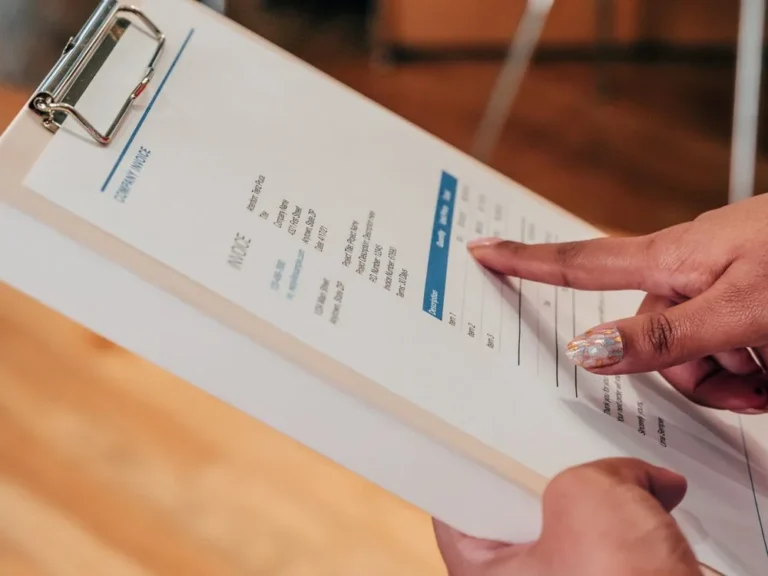 Hand pointing at an invoice on a clipboard