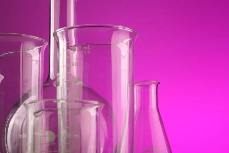 Laboratory glass beakers and flasks on a pink background