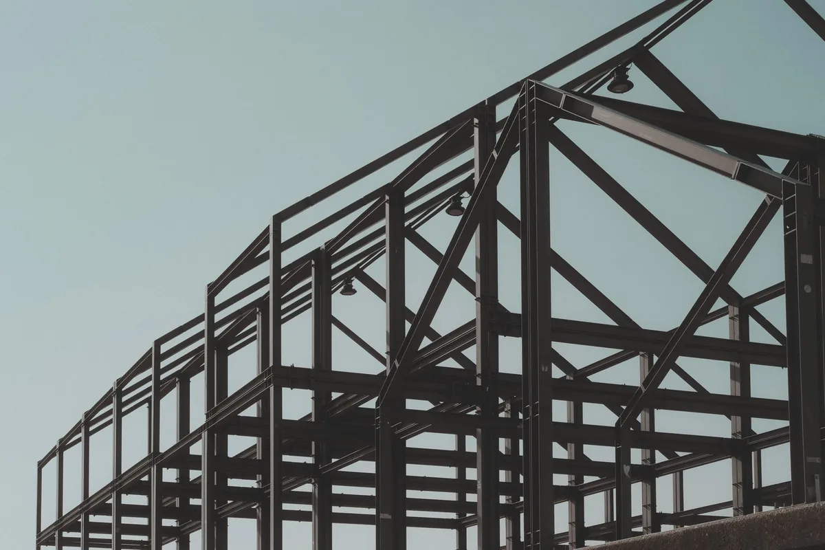 Light steel frame roof structure seen against a pale sky
