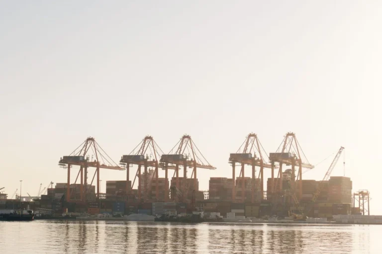 Port cranes and container stacks at sunrise