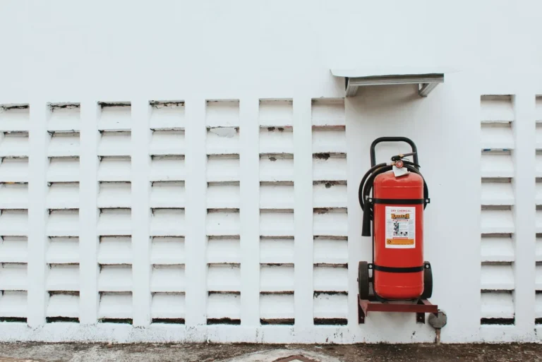 Red fire extinguisher mounted on a plain wall